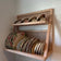 Customer image from a review of a wall mounted plate rack. Cups are placed on the top shelf with saucers decorative placed on top. Plates and bowls are on display on the bottom shelf.