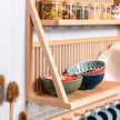 A side view of the bottom shelf of our kitchen storeage rack. Bowls are being displayed in the foreground whilst jars hold dried food along the top. 