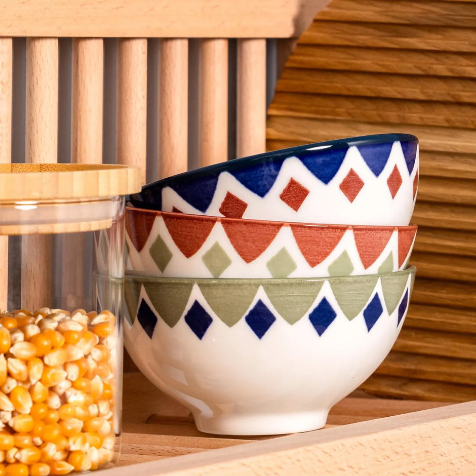 Detailed shot of the top shelf of our wall mounted plate rack, with bowls and a storage jar on display. There is also a wooden kitchen chopping board. 